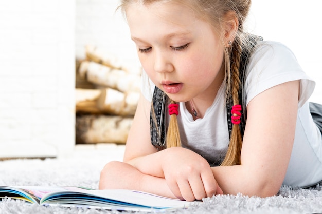 Niña Linda Está Leyendo Un Libro Sobre Una Alfombra En Un Apartamento Foto Premium