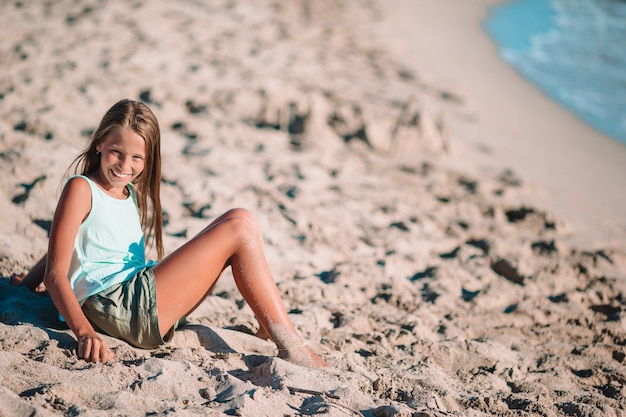 Niña en la playa juega con arena al atardecer Foto Premium
