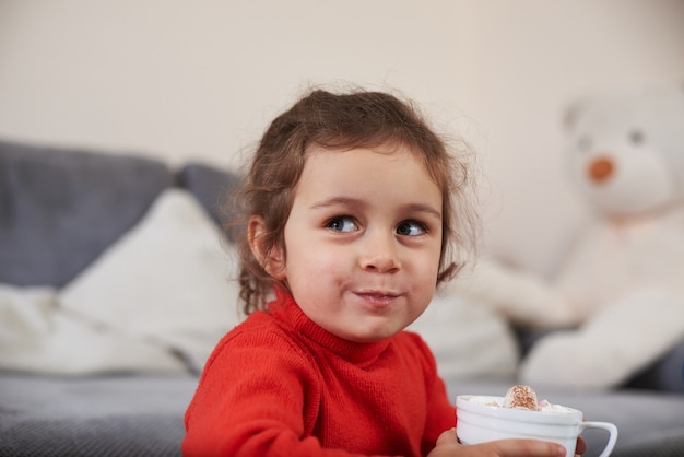 Una Nina Sonriente Se Siente Feliz Mientras Bebe Un Chocolate Con Malvaviscos Foto Premium