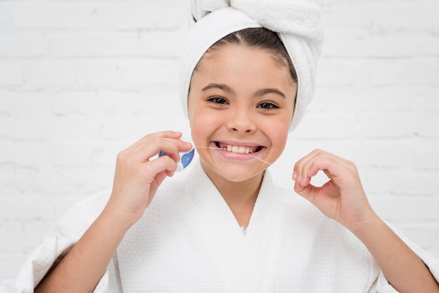 Niña usando hilo dental Foto gratis