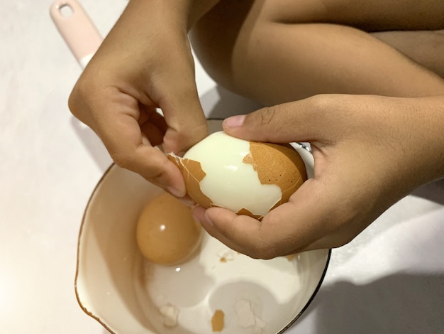 Niño asiático está pelando huevo duro | Foto Premium