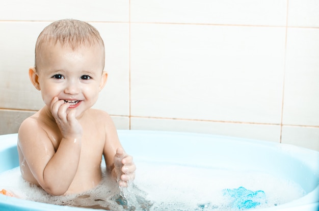 Niño en edad preescolar chico guapo bañándose en el baño limpio e ...