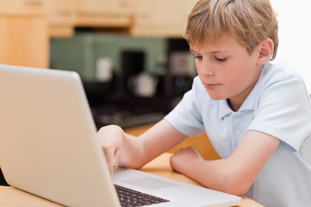 Niño enfocado usando una computadora portátil | Foto Premium