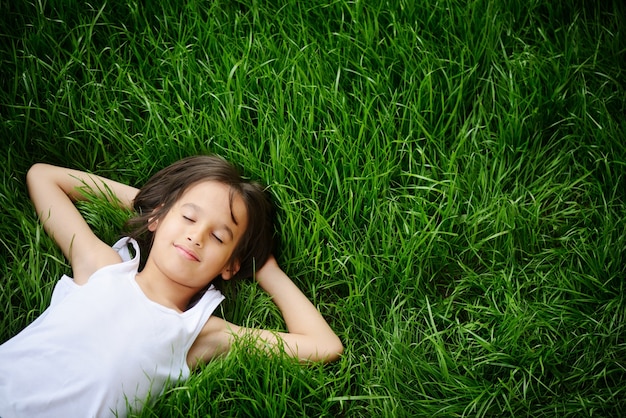 Niño feliz disfrutando en campo de hierba y soñando | Foto Premium