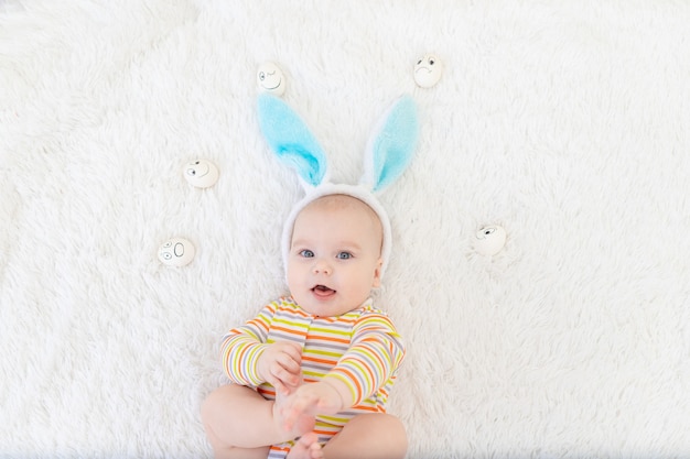 Niño con orejas de conejo en la cabeza se encuentra con huevos con