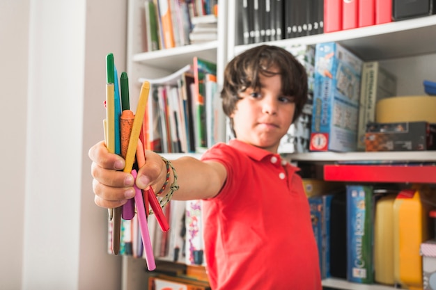 Niño parado con lápices para colorear | Foto Gratis