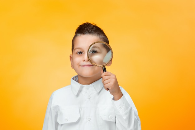 Niño pequeño con lupa mirando de cerca Foto gratis