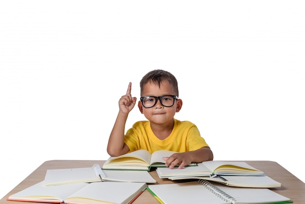 El niño pequeño con el pensamiento de los vidrios y muchos reservan en la tabla. concepto de regreso a la escuela, aislamiento Foto Premium