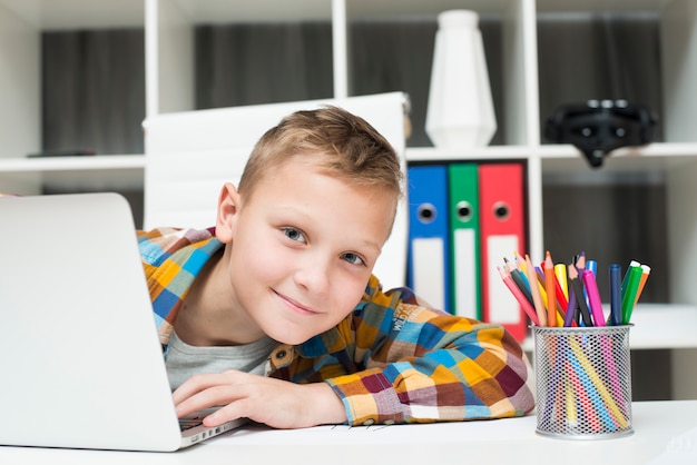 Niño con portátil en escritorio Foto gratis