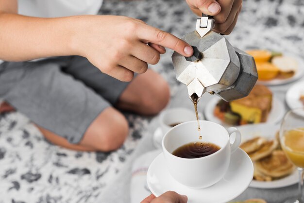 Un niño sirviendo café negro en una taza para otra persona en el ...