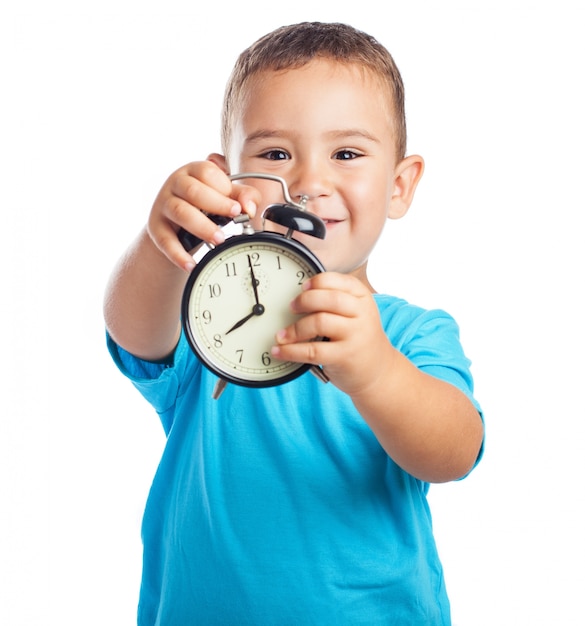 Niño sonriente mostrando un reloj despertador | Foto Gratis