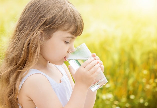 El niño sostiene un vaso de agua en sus manos. enfoque selectivo Foto Premium