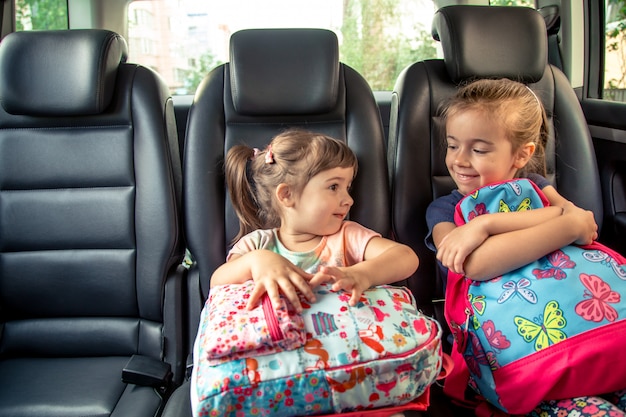 Los niños en el auto van a la escuela, felices y dulces rostros de hermanas Foto gratis