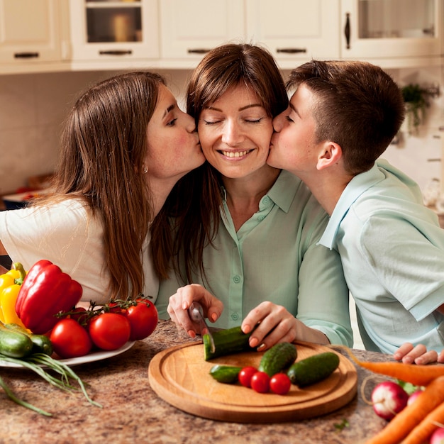 Ninos Dando Un Beso A La Madre En La Cocina Mientras Preparan La Comida Foto Gratis