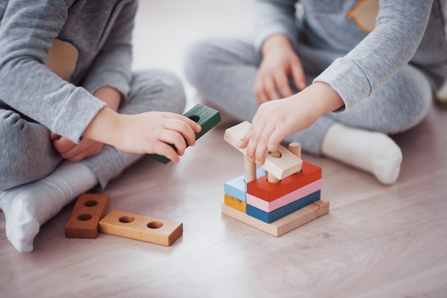 Los niños juegan con un diseñador de juguetes en el piso de la habitación de los niños. dos niños jugando con bloques de colores. juegos educativos de jardín de infantes Foto gratis