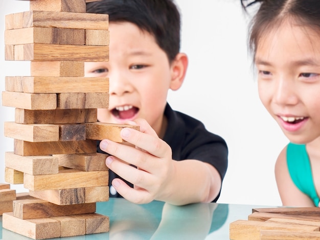 Los niños juegan jenga, un juego de torre de bloques de madera ...