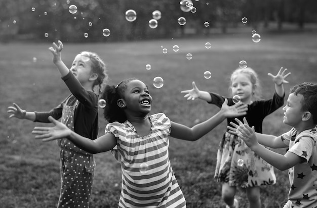 Niños jugando burbujas en un parque | Foto Premium