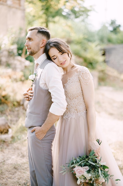 La Novia Con Un Ramo En La Mano Abraza Al Novio Por Detrás Con La Cabeza Sobre Su Hombro Foto 8201