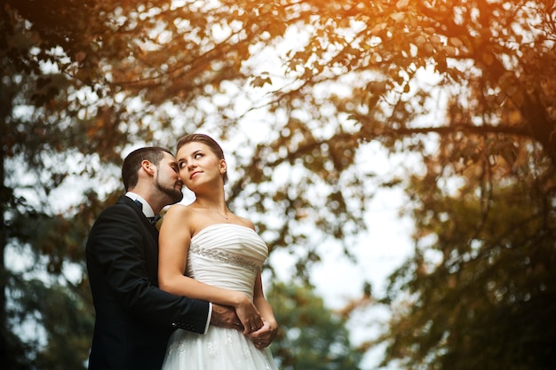 El Novio Abraza Suavemente A La Novia Con Un Ramo Desde Atrás En Un Parque Foto Premium 1010