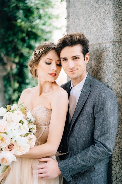 Novio Sonriente Abraza A La Novia Con Un Ramo De Flores Apoyado Contra El Arco Foto Premium 9265