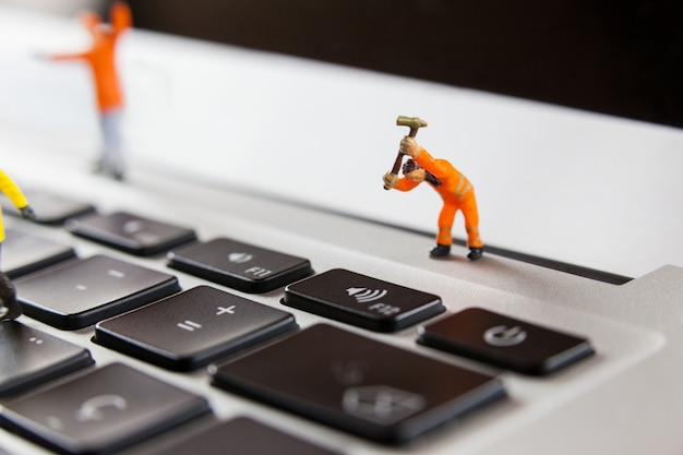 Obreros en miniatura que reparan un teclado portátil