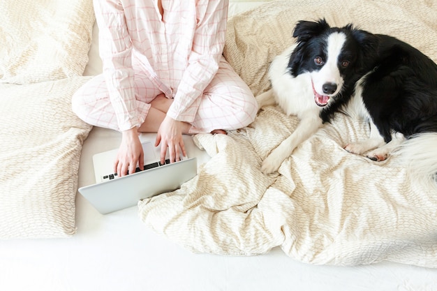 Oficina móvil en casa. mujer joven en pijama sentado en la cama con un  perro mascota