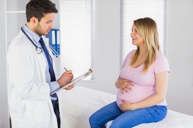Paciente Embarazada Sonriente Hablando Con El Médico Que Está Tomando Notas Foto Premium 9761