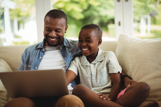 Padre e hijo usar la computadora portátil en sala Foto Premium