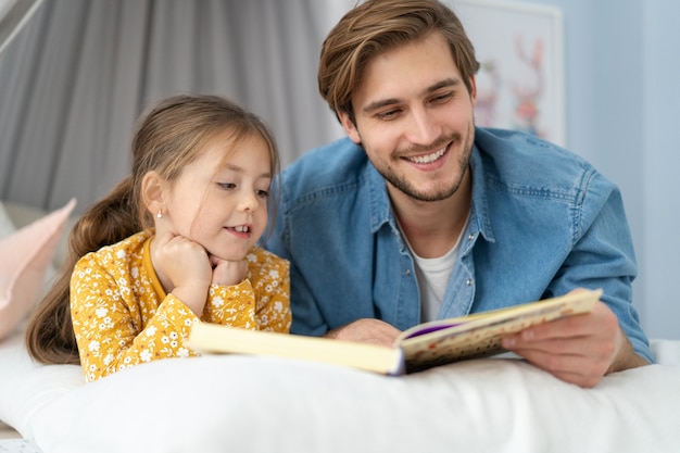 Padre leyendo un libro a su hija mientras está acostado en el suelo en