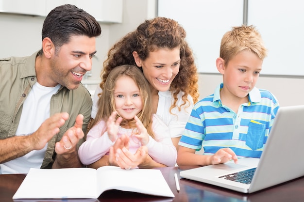 Padres felices que usan la computadora portátil con sus niños ...