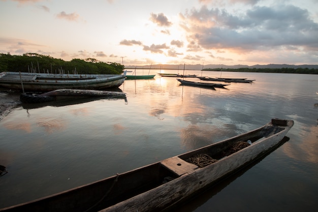 Paisaje con puesta de sol con canoas de pesca en la orilla del río Foto Premium