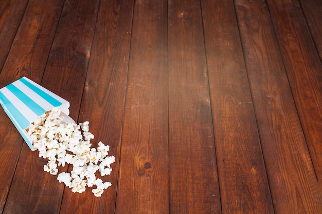 Palomitas de maíz derramado sobre la mesa de madera | Foto Gratis