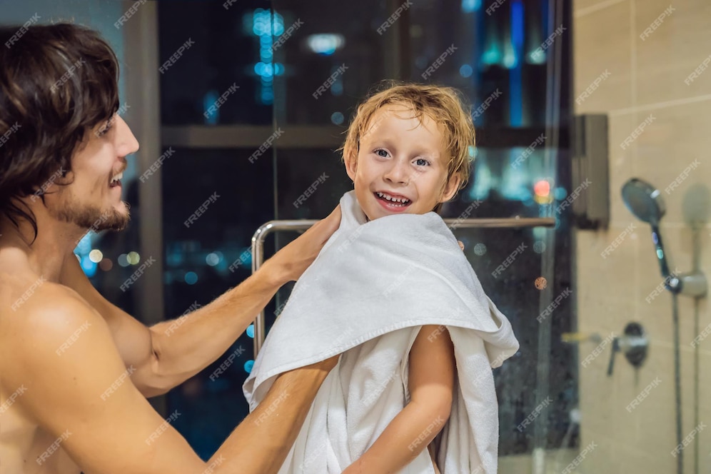 Papá Limpia A Su Hijo Con Una Toalla Después De Una Ducha Por La Noche Antes De Irse A Dormir En