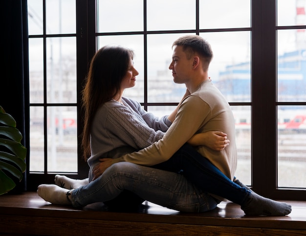 Pareja Abrazada Y Mirándose Frente A La Ventana Foto Gratis 0765