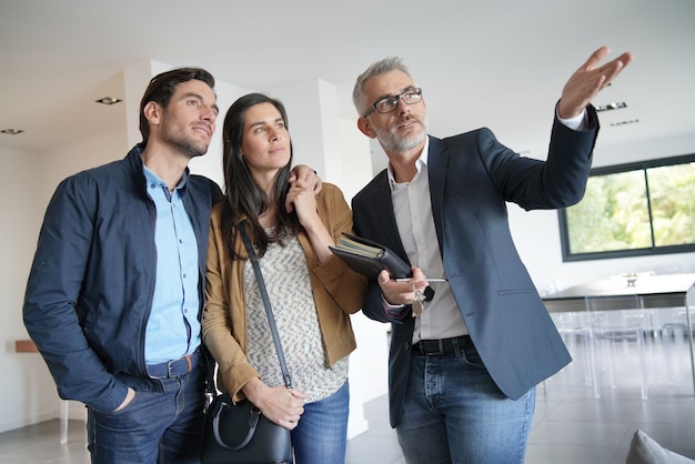 Pareja con agente inmobiliario visitando casa moderna Foto Premium