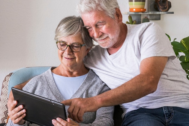 Pareja De Ancianos Sonriendo Y Mirando La Misma Tableta Abrazados En El