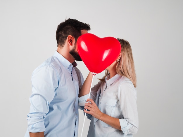 Pareja besándose detrás del globo para san valentín Foto gratis