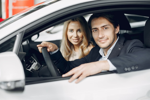 Pareja elegante y elegante en un salón de autos Foto gratis