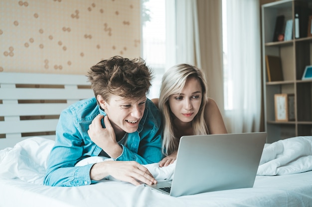 Pareja Feliz Usando La Computadora Portátil En La Cama Foto Gratis