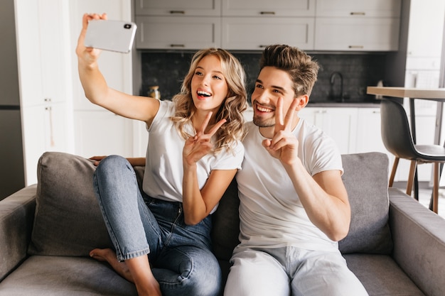 Pareja Joven Alegre En Casa Haciendo Selfie Con Signo De La Paz Y Sonriendo Ampliamente Niña