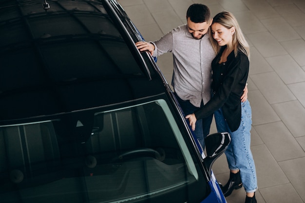 Pareja Joven Eligiendo Un Automóvil En Una Sala De Exhibición De Autos Foto Gratis 