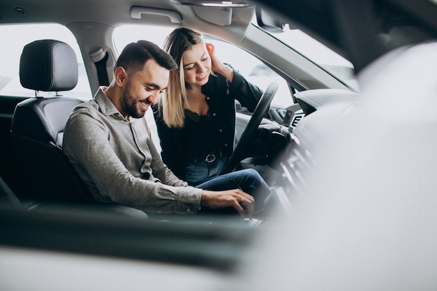 Pareja Joven Eligiendo Un Automóvil En Una Sala De Exhibición De Autos Foto Gratis 