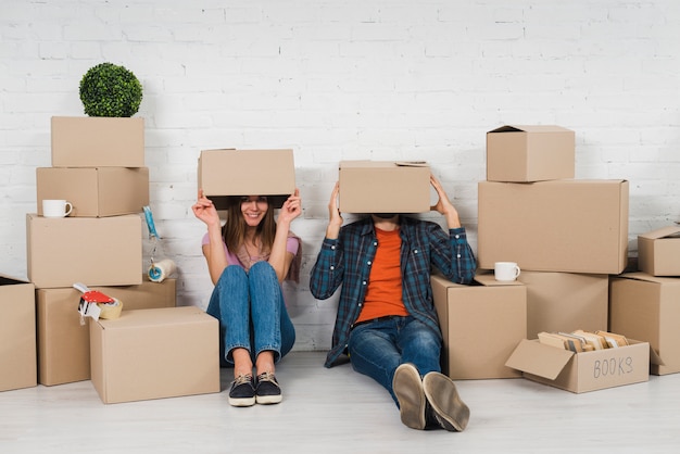 Pareja Joven Escondiendo Su Cara Sentada Entre Las Cajas De Cartn En