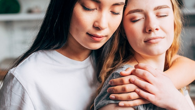 Pareja de lesbianas abrazando con los ojos cerrados Foto gratis