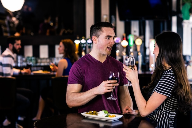 Pareja tomando un aperitivo con vino en un bar | Foto Premium