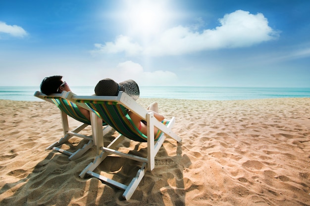 Pareja tomando el sol en una silla de playa y una sombrilla | Foto Premium