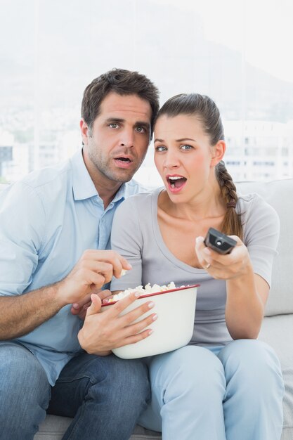 Pareja Viendo La Película De Miedo En El Sofá Con Tazón De Palomitas De Maíz Foto Premium