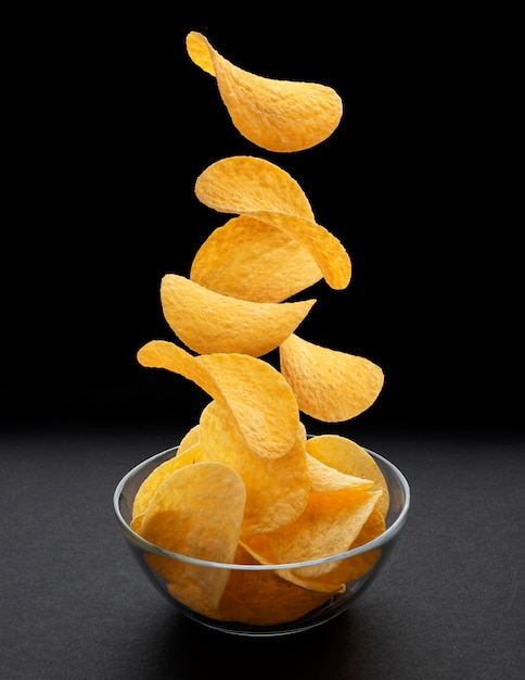 Patatas Fritas Cayendo En Un Tazón De Vidrio Sobre Fondo Negro | Foto ...