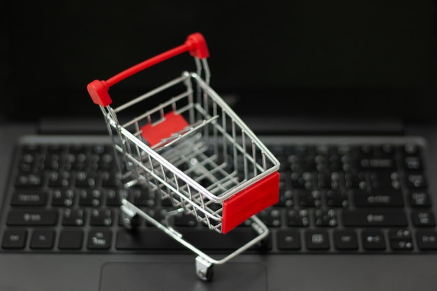 Pequeño carrito de compras en la computadora portátil para compras en línea. concepto de compras en línea Foto Premium