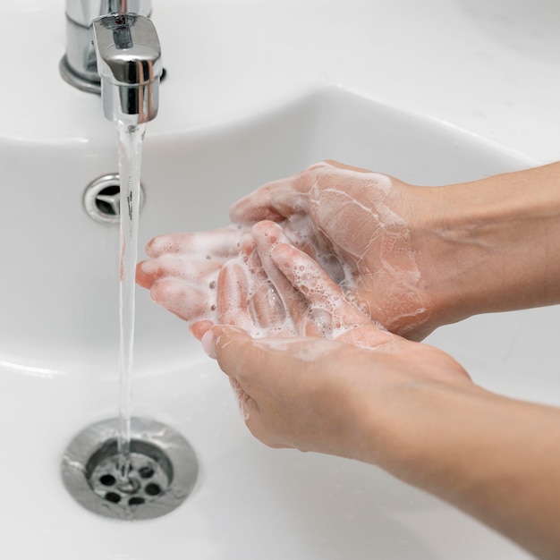 Persona de alto ángulo lavándose las manos en un fregadero Foto gratis